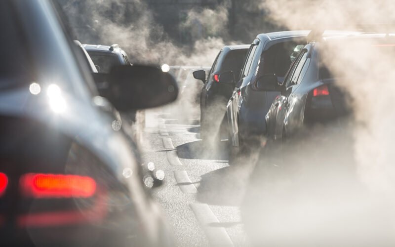 Blurred silhouettes of cars surrounded by steam from the exhaust