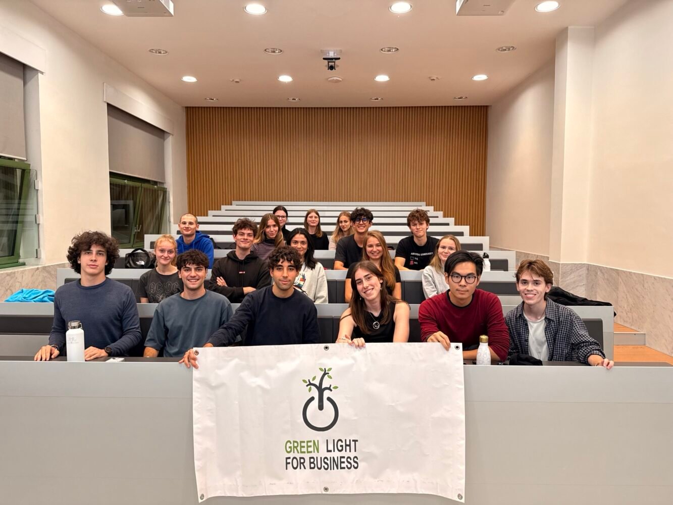 Members of Green Light for Business in a Bocconi lecture hall, holding the association banner